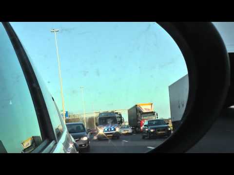 Auto van Ministerie van Defensie met zwaailicht en sirene tussen file door, 12 maart 2015